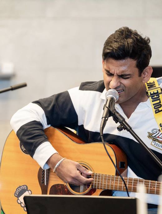Anand Singh singing and playing acoustic guitar